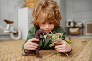 boy playing with 2 dinosaur toys